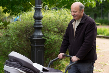 Grandfather pushing newborn in stroller in park