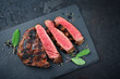 Barbecue dry aged wagyu rib-eye beef steaks with herb and black salt served as top view on a black board with copy space