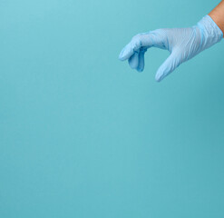 Wall Mural - Doctor's hand in a blue medical glove holds an object on a blue background