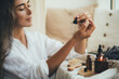© polinaloves - Young woman applying natural organic essential oil on hair and skin. Home spa and beauty rituals.
