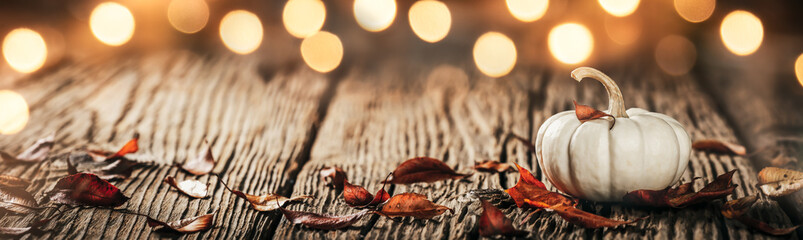 Wall Mural - mini white pumpkin and leaves on wooden harvest table with bright bokeh lights - autumn decoration b