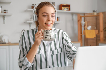 Sticker - Young woman drinking tea while video chatting in kitchen