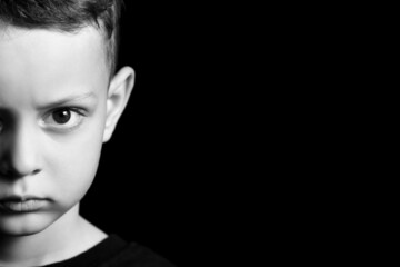 Poster - Black and white portrait of angry little boy on dark background