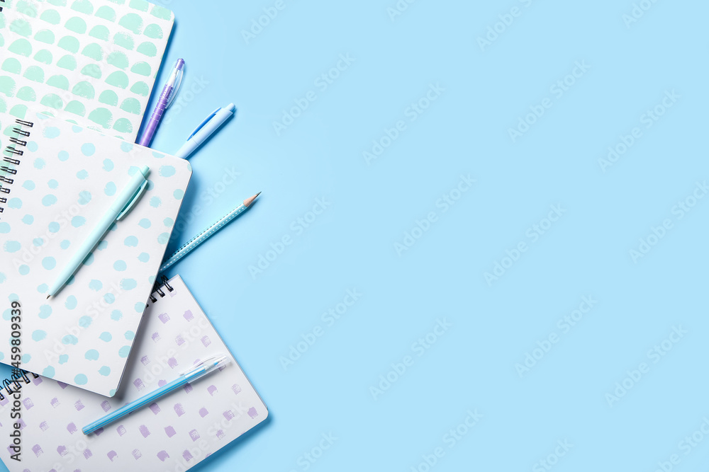 Stylish notebooks, pens and pencil on color background, closeup