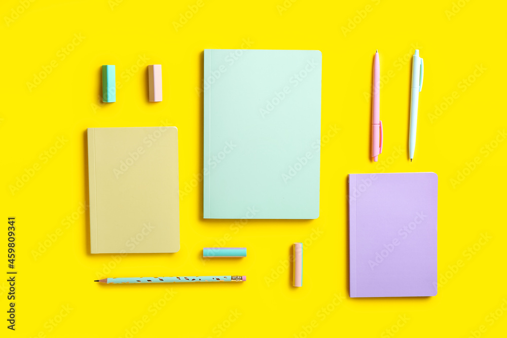 Stylish notebooks, pens, pencil and erasers on color background