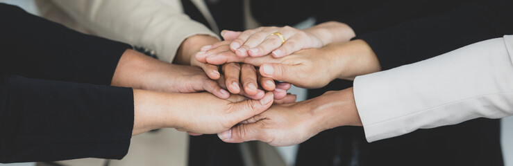 Close up shot of holding hands of unidentified unrecognizable successful female businesswoman group together in formal business suit wears empower encourage as trust teamwork partnership agreement