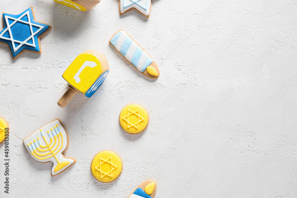 Tasty cookies for Hanukkah celebration and dreidels on light background