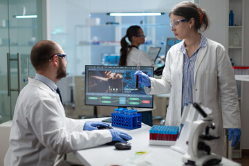 Wall Mural - medical team examining blood sample discussing virus expertise during medicine experiment in biochem