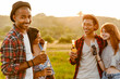 © Drobot Dean - Multiracial two couples drinking beverages and laughing while hiking