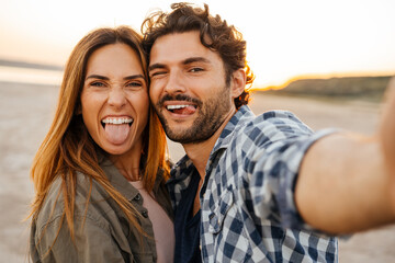 White young couple showing their tongues while taking selfie photo