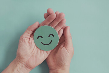 Wall Mural - Hands holding green happy smile face paper cut, good feedback rating,positive customer review, experience, satisfaction survey ,mental health assessment, child wellness,world mental health day concept