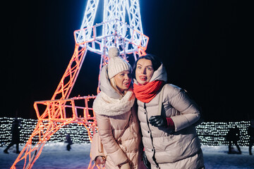 Wall Mural - two girls in winter with New Year's eve lights burning on Christmas street