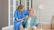 © AboutLife - Smiling blonde nurse in uniform takes care of senior woman sitting in comfortable armchair