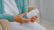 © AboutLife - Senior woman in casual clothes holds blank white bottle of pharmacy sitting in comfortable armchair