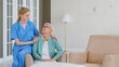 © AboutLife - Smiling blonde nurse in uniform takes care of senior woman in light room at assisted living