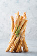 Italian grissini breadsticks with sesame and rosemary on a light background, selective focus