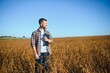 © Serhii - farmer agronomist in soybean field checking crops before harvest. Organic food production and cultivation.