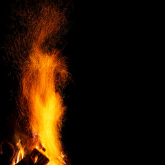 A bonfire with a column of sparks on a black background with a free space, a square frame.