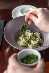 Wall Mural - person eating pelmeni Dumplings with parsley and sour cream