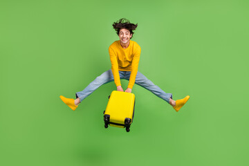 Poster - Full length body size photo jumping man keeping luggage in airport isolated pastel green color background