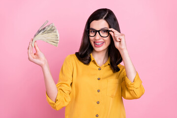 Wall Mural - Photo of funny brunette hairdo millennial lady show money wear yellow shirt eyewear isolated on pink color background