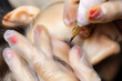 the hands of the master of permanent makeup who performs the tattoo of the eyelid of the model bent over her