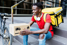 Smiling Delivery Man With Package Sitting On Steps