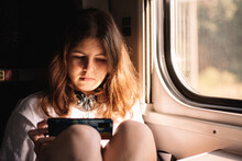Teenage Girl Using Smart Phone While Traveling In Train