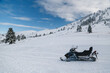 Snowmobile without people on ski slope with splendid snow-covered mountains view in background. Winter vacation