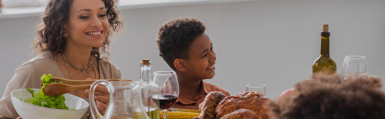 Wall Mural - African american mother and son sitting near thanksgiving dinner, banner