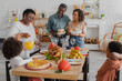 © LIGHTFIELD STUDIOS - Smiling african american family serving thanksgiving dinner near blurred kids