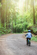 a small child in a helmet learns to ride a two-wheeled bicycle on forest paths. joint time of parents and children, active recreation