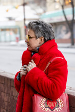 Stylish Mature Woman In Red Coat With Handbag On Urban Street