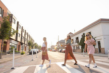 Cheerful Girlfriends Walking Across Street In Town