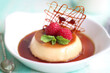 Selective focus of French caramel custard pudding in plate with spun sugar decoration, mint leaf and raspberries 