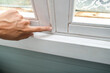 Woman hand insulating old windows to prevent warmth heat leak and drafts, preparing house for winter and cold weather