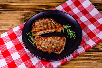 Wall Mural - Plate with roasted steaks and rosemary twigs on a wooden table