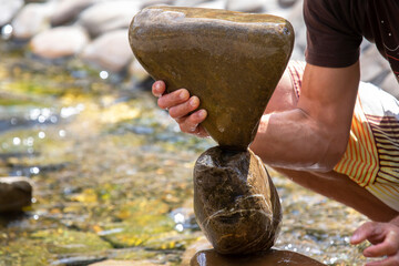 Wall Mural - human hands build a cairn of stones on the water. balance and meditation