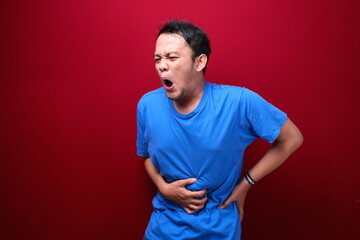 Wall Mural - Upset young asian man with serious stomach ache