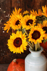Fotomurales - Bouquet of sunflowers in a ceramic vase and orange pumpkins around it.