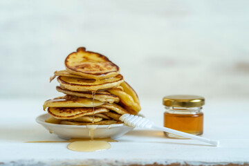 Wall Mural - Apple pancakes with fresh honey over white wooden background with copy space.