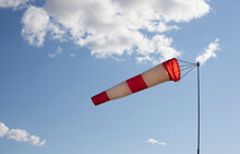 White And Red Wind Flag (windsock) With Blue Sky Background. Air Sleeve On A Sunny Day Indicating Direction Of Wind. Windy Weather Concept.