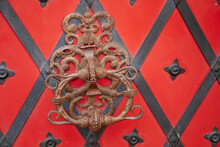 Hustopece, Southern Moravia, Czech Republic, 04 July 2021: Renaissance burgher house U Synku, welcome forged door handle with picture of green man, growing irradiators, red door in black metal billet