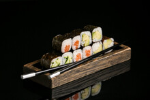 Wooden Tray With Delicious Maki Rolls And Chopsticks On Dark Background