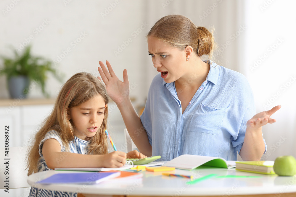 Little girl with her mother doing lessons at home