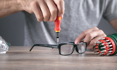 Wall Mural - Optical technician repairing eyeglasses with screwdriver.