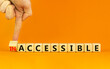 Accessible or inaccessible symbol. Businessman turns a wooden cube, changes the word Inaccessible to Accessible. Beautiful orange background, copy space. Business, accessible or inaccessible concept.
