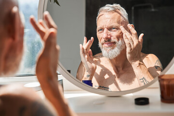 Mature man applying anti-aging cream on his face