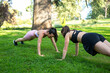 © luisrojasstock - two young caucasian girls practicing push-ups in a park on a sunny day