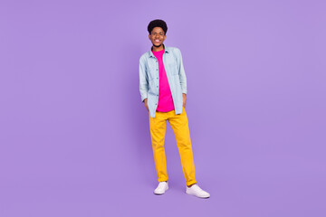 Wall Mural - Photo of cute funny dark skin guy dressed jeans shirt arms pockets smiling isolated violet color background